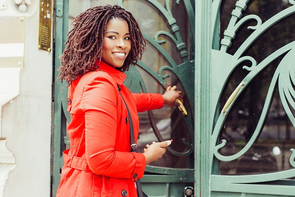 Woman,Opening,Door,And,Smiling,At,Camera.,Cheerful,Young,African Woman,Opening,Door,And,Smiling,At,Camera.,Cheerful,Young,African